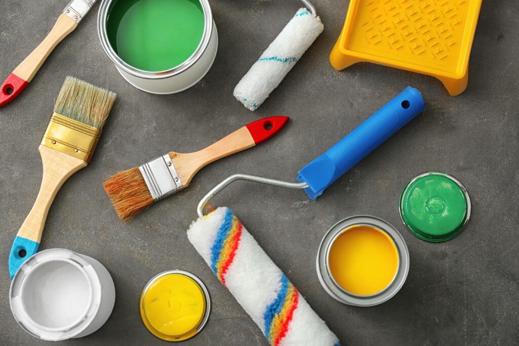 cans-paint-roller-brushes-grey-background-min